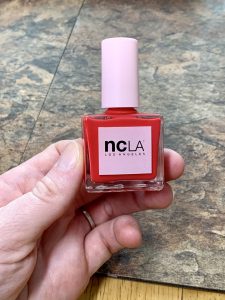hand holding NCLA red nail polish