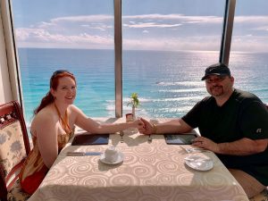 couple holding hands at breakfast in front of an oceanview windo