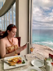 woman looking at menu at table at oceanfront restaurant