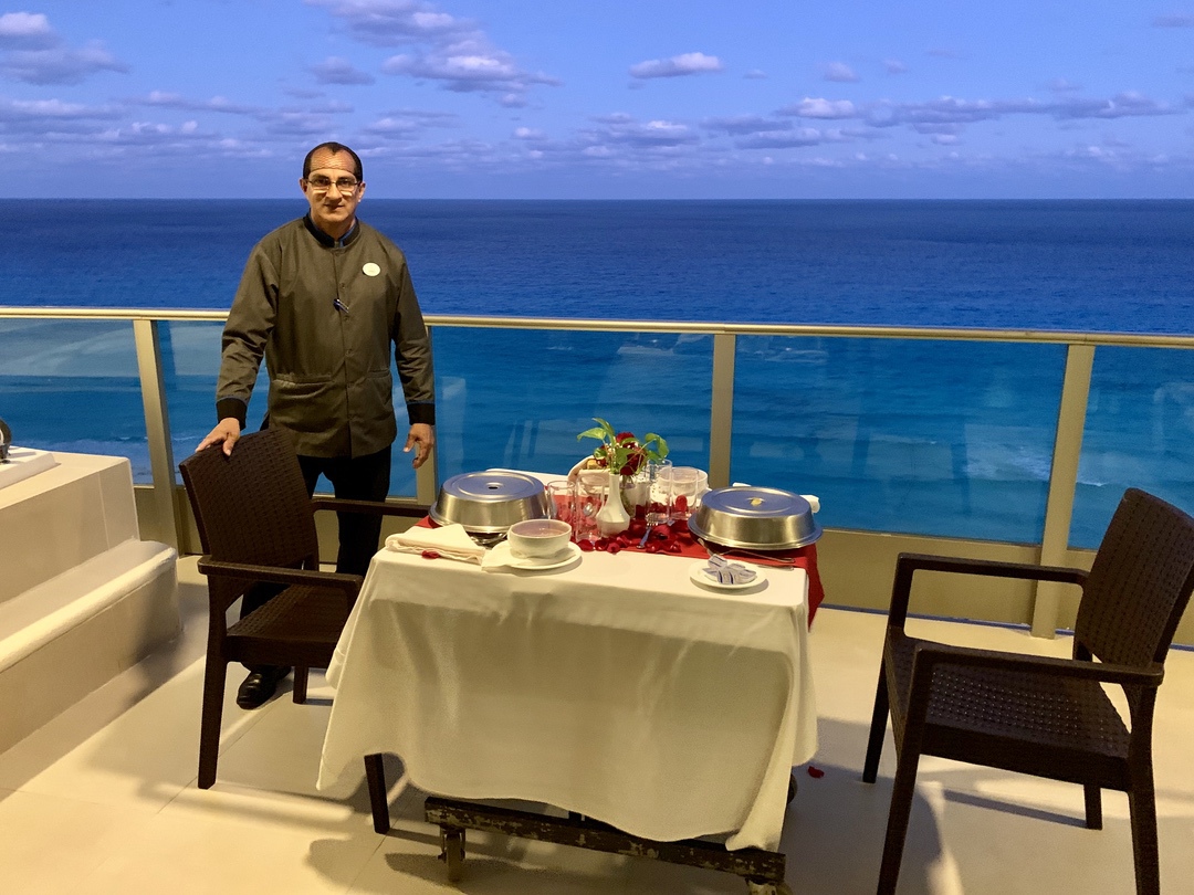 server at table on balcony with ocean view