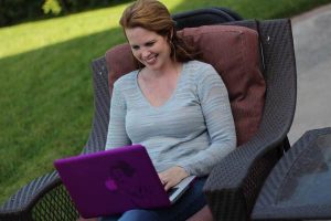 A redhead woman sitting using a laptop