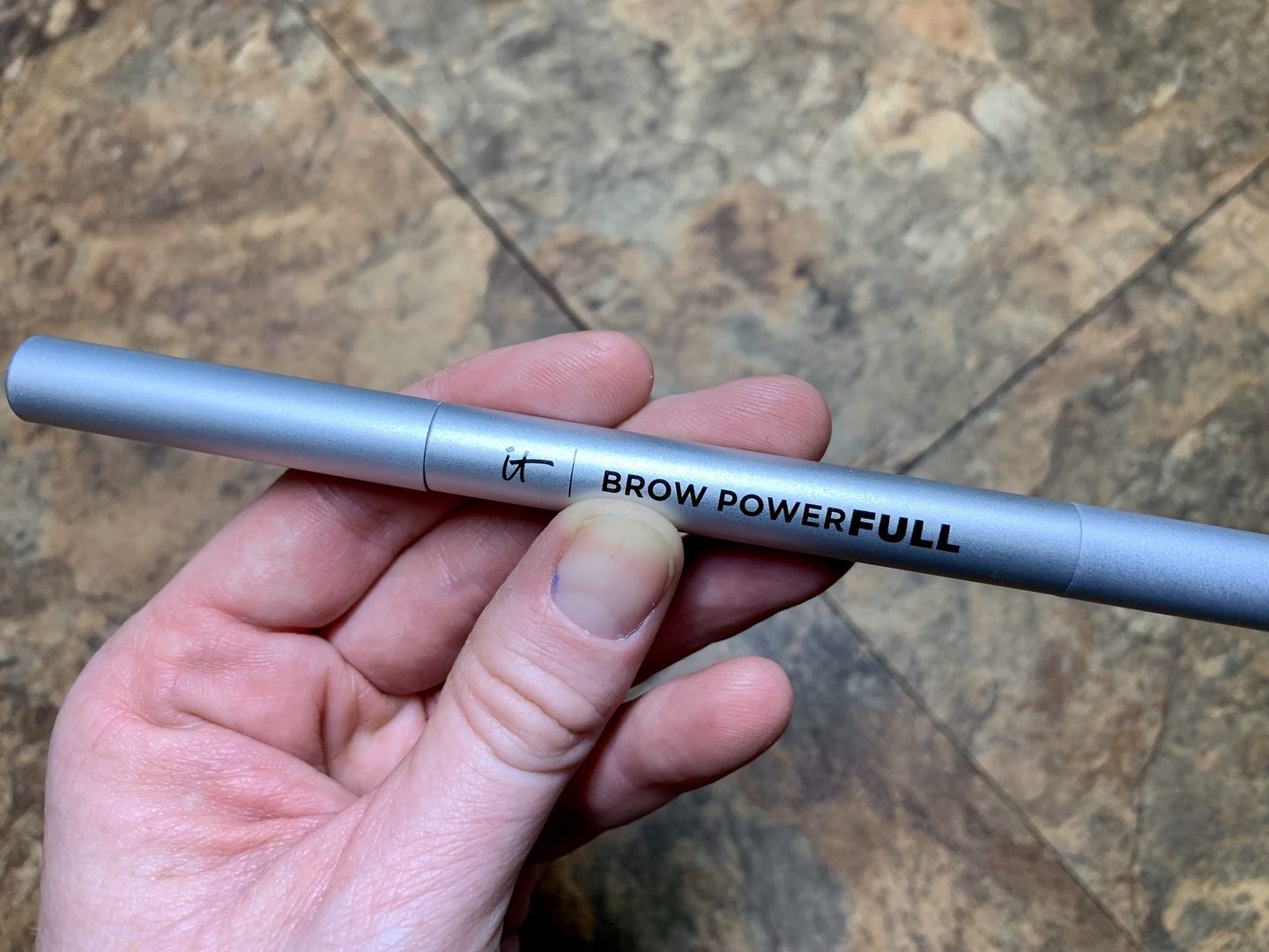 A hand holding an eyebrow pencil