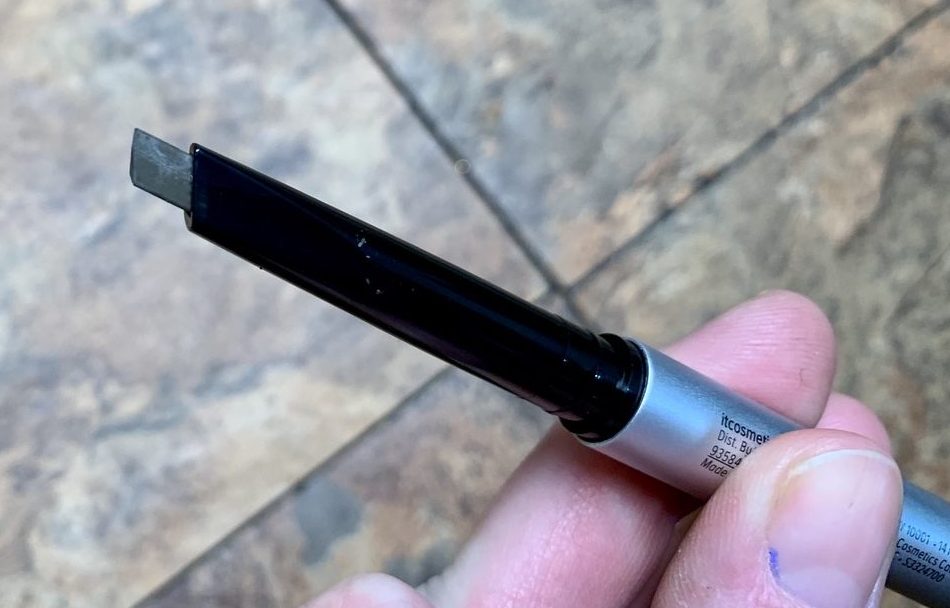 A hand holding an eyebrow pencil