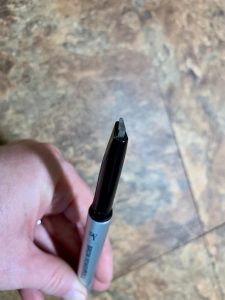 A hand holding an eyebrow pencil