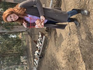 a woman holding a basket of eggs in front of chickens