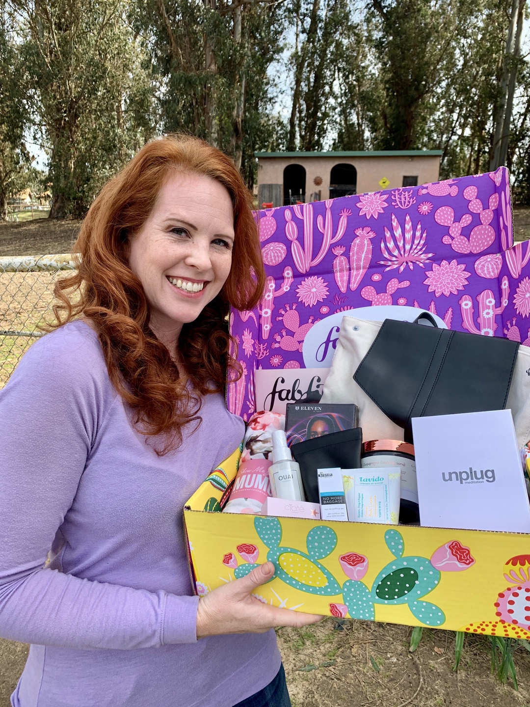 A woman holding a subscription box from FabFitFun