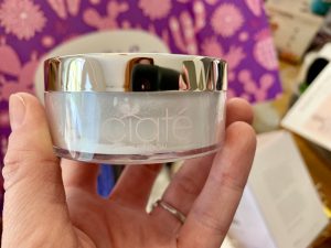 A hand holding a container of makeup
