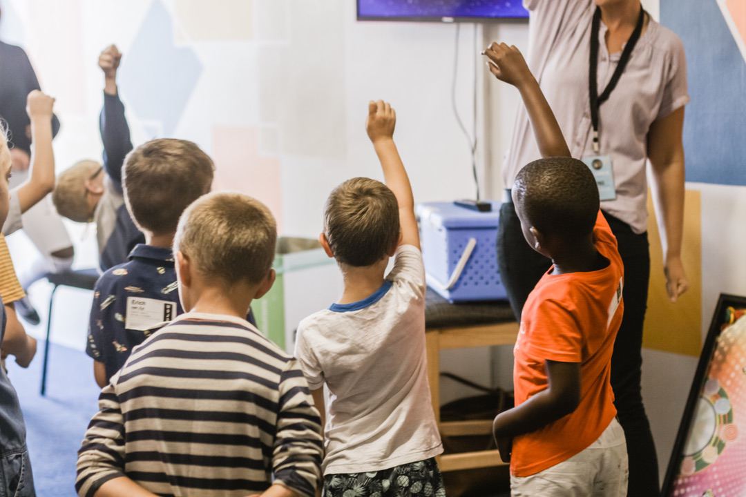 students raising hands in classroom