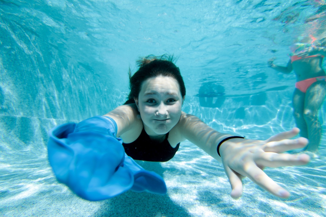 Girl swimming under water in pool with waterproof cast cover