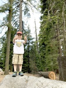 boy standing on rock with two thumbs up