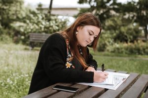Woman Writing Essay on Table Outside