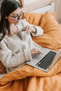 woman with sweater and blanket and tea with laptop