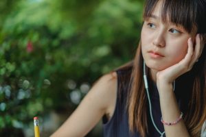 Woman Thinking about Writing with Pencil and Headphones