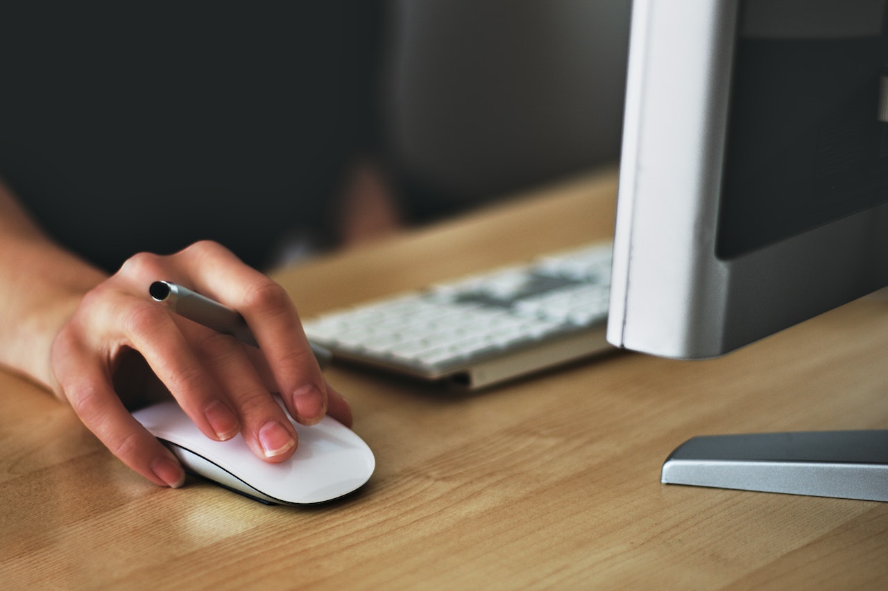 hand on mouse by computer monitor