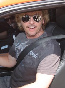 David Spade wearing sunglasss sitting in a car