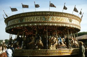 A group of people standing in front of a merry go round