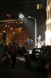 A group of people walking on a city street with film crew